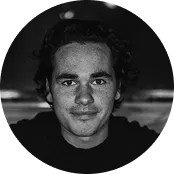 Black and white close-up portrait of a young man with curly hair and a slight smile.